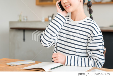 自宅のリビングでスマホで通話する小学生,中学生の女の子 自宅のリビングでスマホで通話する小学生,中学生の女の子 130589729