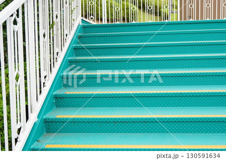 緑色に塗装された鉄製の屋外階段と白い手すり 幾何学模様が美しい工業的デザイン 130591634