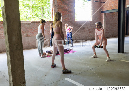A group of women actively engaged in various exercises within a modern gym environment A group of women actively engaged in various exercises within a modern gym environment 130592782