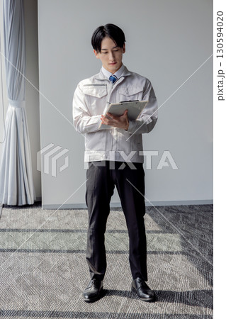 タブレットを使う作業服の男性 130594020