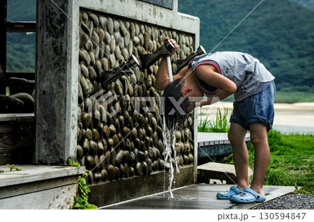 ＜素材＞海水浴に来て顔と頭を洗う男の子 130594847