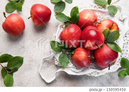 Fresh red apples with leaves in reusable shopping bag on table 130595450