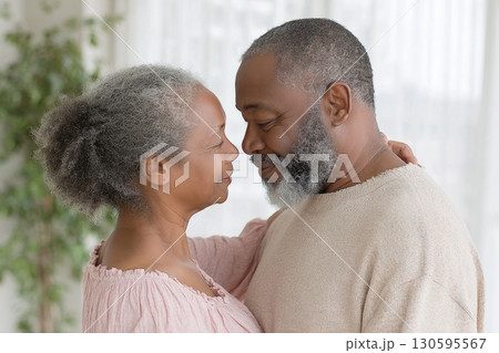 Elderly couple dancing together in a softly lit room, smiling and holding each other closely, sharing a tender and joyful moment Elderly couple dancing together in a softly lit room, smiling and holding each other closely, sharing a tender and joyful moment 130595567