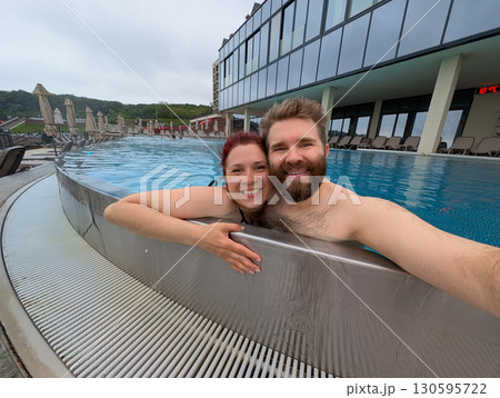 Happy couple embracing in outdoor pool. Love, relaxation, and joyful holiday moment. Happy couple embracing in outdoor pool. Love, relaxation, and joyful holiday moment. 130595722