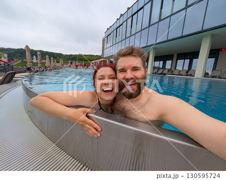 Couple smiling together in the pool. Love, bonding, and joyful summer vacation. 130595724
