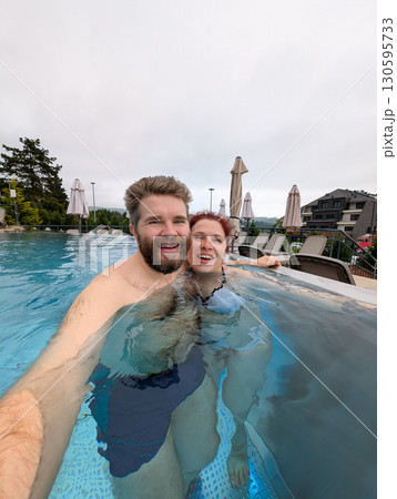 Couple smiling together in the pool. Love, bonding, and joyful summer vacation. 130595733