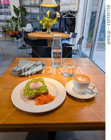 Avocado toast with poached egg and salmon served on a plate in a cafe. Healthy breakfast, fresh ingredients, and gourmet dining. Avocado toast with poached egg and salmon served on a plate in a cafe. Healthy breakfast, fresh ingredients, and gourmet dining. 130595756