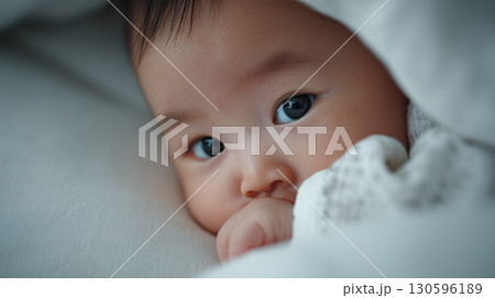 布団に包まれて指をくわえるかわいい赤ちゃんの表情「生成AI」 130596189