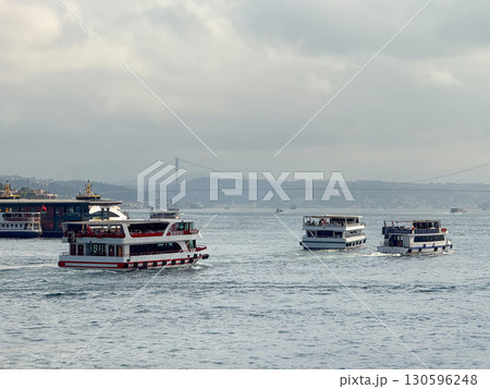 Passenger boats navigating the Bosphorus with bridge in the background. Transportation, tourism, and urban maritime life in Istanbul. 130596248