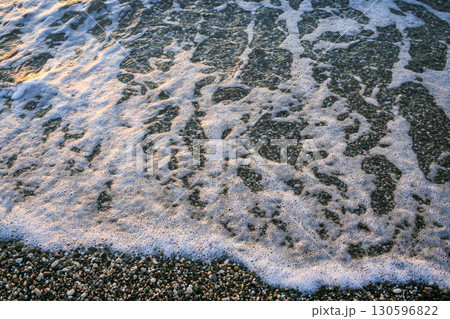 Ocean waves gently lapping against pebbled shore creating serene coastal atmosphere Ocean waves gently lapping against pebbled shore creating serene coastal atmosphere 130596822