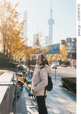 woman traveler visiting in Shanghai, China. Female Tourist with backpack sightseeing Shanghai view of Lujiazui in The north Bund of Shanghai in Autumn. landmark and popular for tourism attractions 130597473