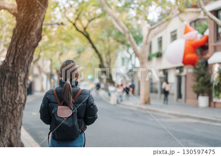 woman traveler visiting in Shanghai, China. Female Tourist with backpack sightseeing in Anfu road during Christmas time. landmark and popular for tourism attractions in Shanghai. Travel and vacation woman traveler visiting in Shanghai, China. Female Tourist with backpack sightseeing in Anfu road during Christmas time. landmark and popular for tourism attractions in Shanghai. Travel and vacation 130597475
