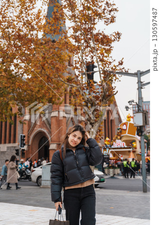 woman traveler visiting in Shanghai, China. Happy Female Tourist sightseeing Shanghai Union Church view in autumn season. landmark and popular for tourism attractions. Travel and vacation 130597487