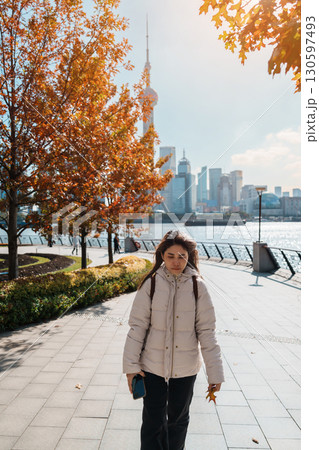 woman traveler visiting in Shanghai, China. Female Tourist with backpack sightseeing Shanghai view of Lujiazui in The north Bund of Shanghai in Autumn. landmark and popular for tourism attractions 130597493