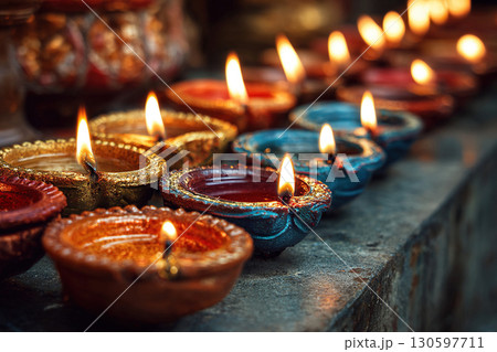 Diyas with lit wicks stand in two rows on a concrete step. Preparations for Diwali. 130597711