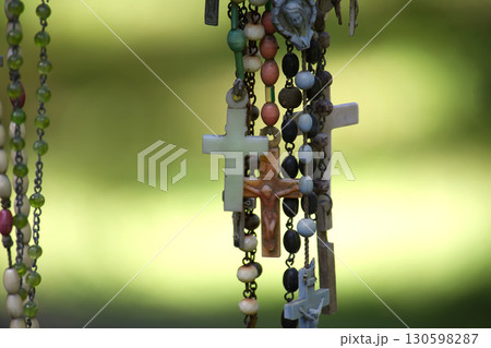 Several rosaries with crosses hang in front of a soft, green backdrop, emphasizing faith and devotion. 130598287