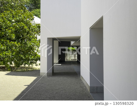 Minimalist white building with geometric passage and shadows next to a green tree in Serralves Park, Minimalist white building with geometric passage and shadows next to a green tree in Serralves Park, 130598320