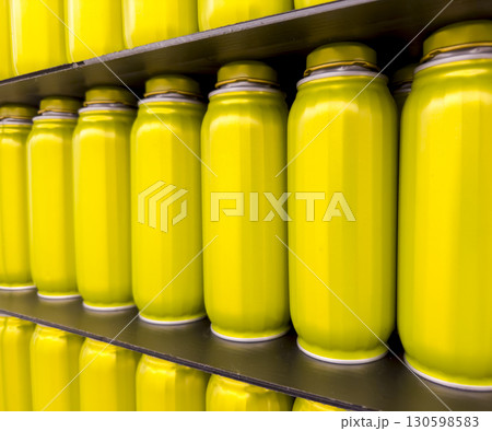 Bright yellow jars, metallic tins, soda bottles arranged on shelves. The repeating pattern of Bright yellow jars, metallic tins, soda bottles arranged on shelves. The repeating pattern of 130598583