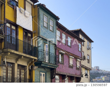 Colorful traditional houses in Porto with tiled facades in yellow, green, and red. Laundry hangs Colorful traditional houses in Porto with tiled facades in yellow, green, and red. Laundry hangs 130598597