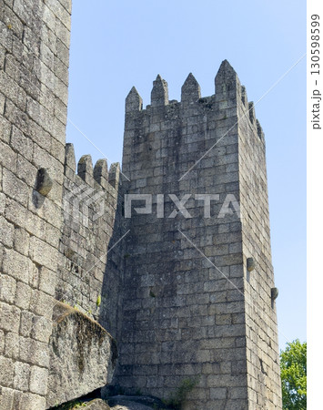 Stone tower of Guimaraes Castle in Portugal under a bright blue sky. The medieval fortress with Stone tower of Guimaraes Castle in Portugal under a bright blue sky. The medieval fortress with 130598599