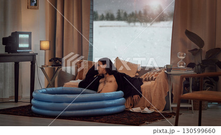 Bored, man and in home sitting in pool in the lounge in a retro home watching vintage TV with no signal. Winter, snow and hipster relaxing in the living room in a house during vacation or a holiday Bored, man and in home sitting in pool in the lounge in a retro home watching vintage TV with no signal. Winter, snow and hipster relaxing in the living room in a house during vacation or a holiday 130599660