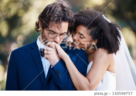 Wedding, kiss on hand and happy couple outdoor for marriage celebration event together with commitment. Interracial man and woman at ceremony with trust, partnership and respect with smile from bride 130599757