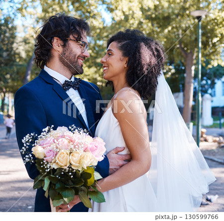 Interracial wedding and couple with flowers and hug at romantic outdoor marriage event celebration together. Partnership, commitment and trust embrace of happy bride and groom with smile. Interracial wedding and couple with flowers and hug at romantic outdoor marriage event celebration together. Partnership, commitment and trust embrace of happy bride and groom with smile. 130599766