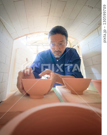 窯に器を並べる陶芸職人の作業風景 窯に器を並べる陶芸職人の作業風景 130599789