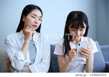 スマホに夢中になる娘を心配する母親のイメージ 130600104