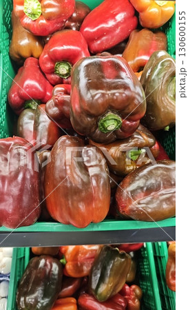 Pile of ripe red and brownish bell peppers in a green crate at the market Pile of ripe red and brownish bell peppers in a green crate at the market 130600155