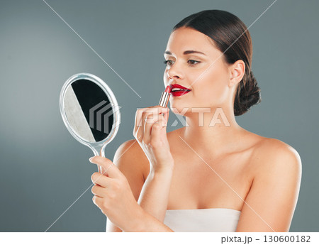 Lipstick, woman and mirror on studio background for beauty, fashion and aesthetics. Young model, red lips and makeup application with reflection for glamour cosmetics, elegant skincare or cosmetology Lipstick, woman and mirror on studio background for beauty, fashion and aesthetics. Young model, red lips and makeup application with reflection for glamour cosmetics, elegant skincare or cosmetology 130600182