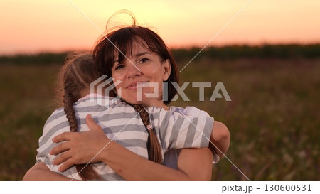 mother woman parent female, child girl kid childhood outdoors, Mother and daughter hugging in a field, Woman embracing child at sunset, Family love and togetherness, Warm evening outdoors, Parent and 130600531