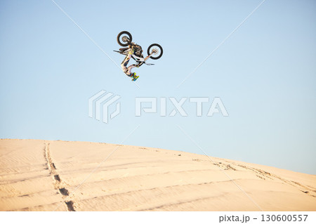 Motorcycle, jump and sports athlete in desert, dirt bike rally outdoor with extreme sport stunt, power and action. Nature, adventure and freedom, fitness challenge and biker person, mockup and travel 130600557