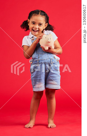 Excited child, portrait and piggy bank in money planning, savings or future investment on isolated red background. Smile, happy and kid with cash box for finance growth, budget learning in studio 130600617