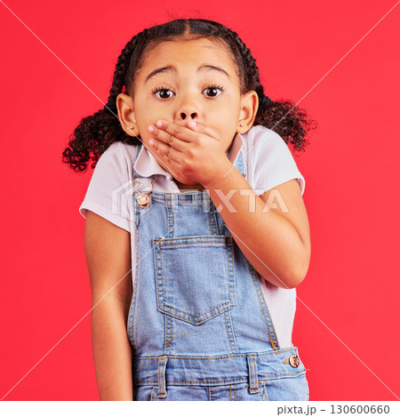 Shocked child, portrait and hand on mouth in secret, oops and mistake facial expression on isolated red background. Kid, little girl and surprised face in gossip, news or emoji at studio announcement 130600660