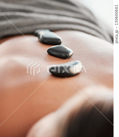 Woman, rocks and back in spa relaxation for treatment, stress relief or massage at resort. Female relaxing with hot stone in physical therapy for skincare, body healing or zen wellness at salon 130600681