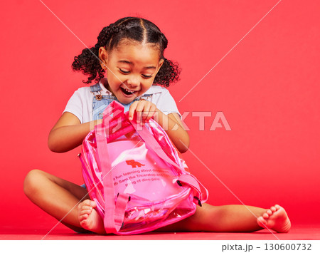 School, bag and red background with a student black girl in studio sitting on the floor against a wall. Children, education and excited with a female kid pupil getting ready for learning, or growth 130600732