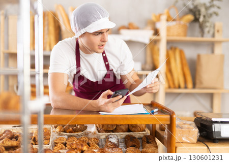 Worried bakery owner reviewing problematic order details using phone 130601231