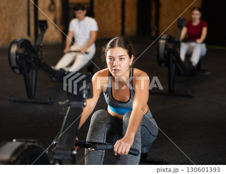 Woman in top exercising on rowing machine Woman in top exercising on rowing machine 130601393