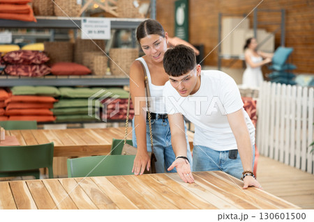 Interested young couple choosing wooden table in store Interested young couple choosing wooden table in store 130601500