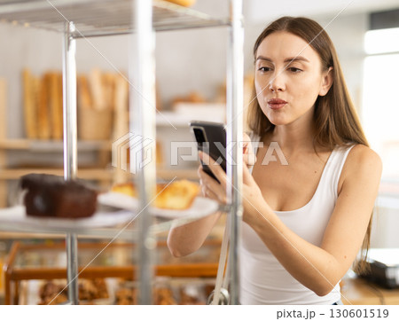 Woman checks calories of cake using app on phone 130601519