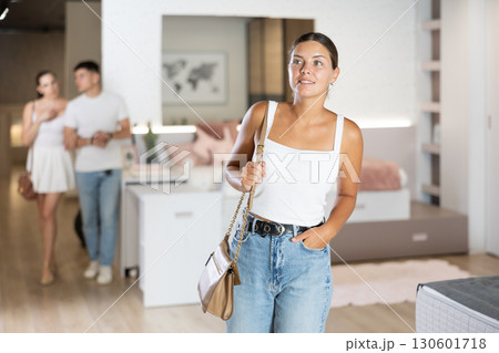 Young woman looking around in bedroom department 130601718