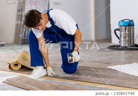 Male repairer installing laminate flooring in apartment Male repairer installing laminate flooring in apartment 130601749