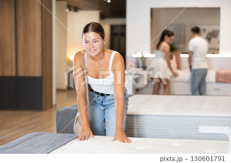 Young smiling woman testing new mattress in furniture store Young smiling woman testing new mattress in furniture store 130601791