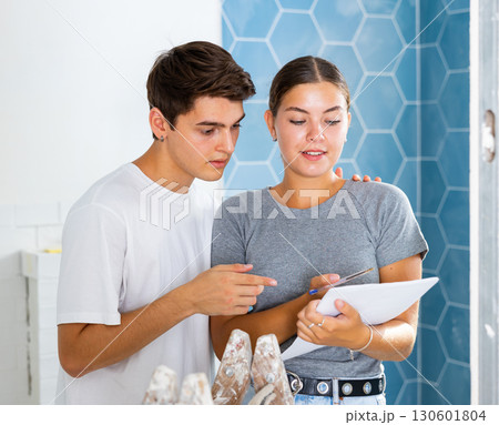 Young couple with documents checks the number of tiles, making important notes Young couple with documents checks the number of tiles, making important notes 130601804