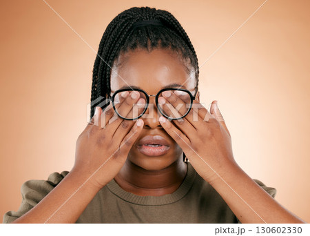 Hands, eyes and glasses with a black woman in studio on a beige background covering her face. Vision, blind and cover with a female indoor to promote eye care or health for the optometry industry 130602330