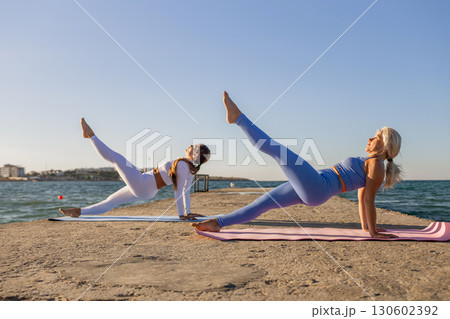 Yoga Women Beach Fitness - Two women practicing yoga on a beach. 130602392