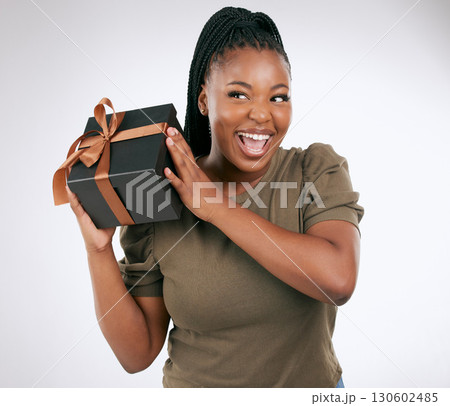 Gift, box and woman guess in studio with package, smile and celebration. Happy, curious and black female with present, surprise and ribbon on background, birthday and giveaway of product promotion Gift, box and woman guess in studio with package, smile and celebration. Happy, curious and black female with present, surprise and ribbon on background, birthday and giveaway of product promotion 130602485