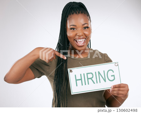 Creative business woman, pointing and hiring sign for recruiting isolated on gray studio background. Portrait of happy African American female manager with board for recruitment, job hire or startup 130602498