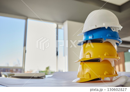 Building, helmets and architect equipment on table for construction safety, security or industrial work gear at office. Stack of hard hats on desk for safe engineering or contracting for architecture 130602827